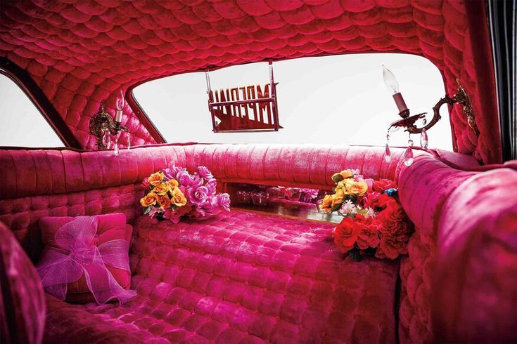 the interior of an old car with pink couches and flowers in front of it