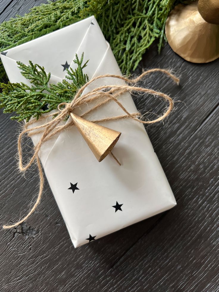 a present wrapped in white paper and tied with twine on top of a wooden table