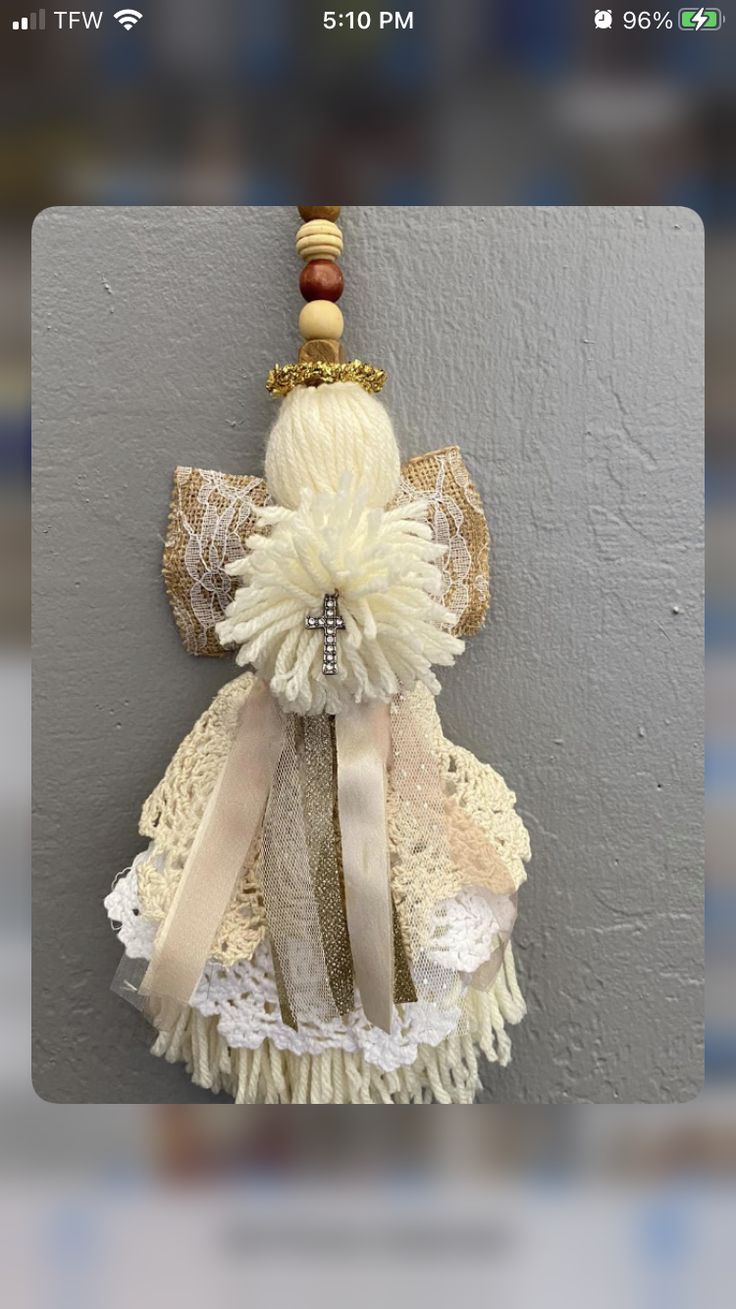 an image of a doll hanging on the wall with lace and ribbon attached to it