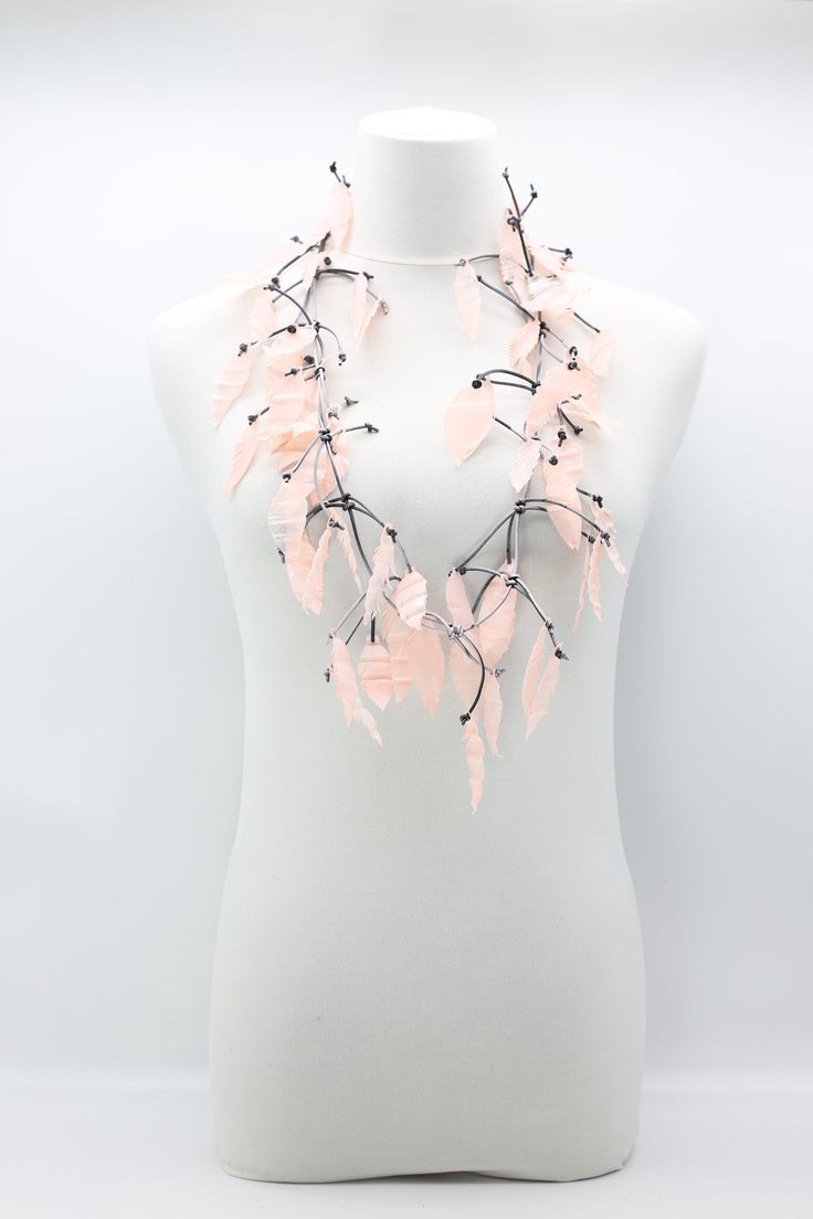 a white mannequin with pink flowers and black stems on it's neck