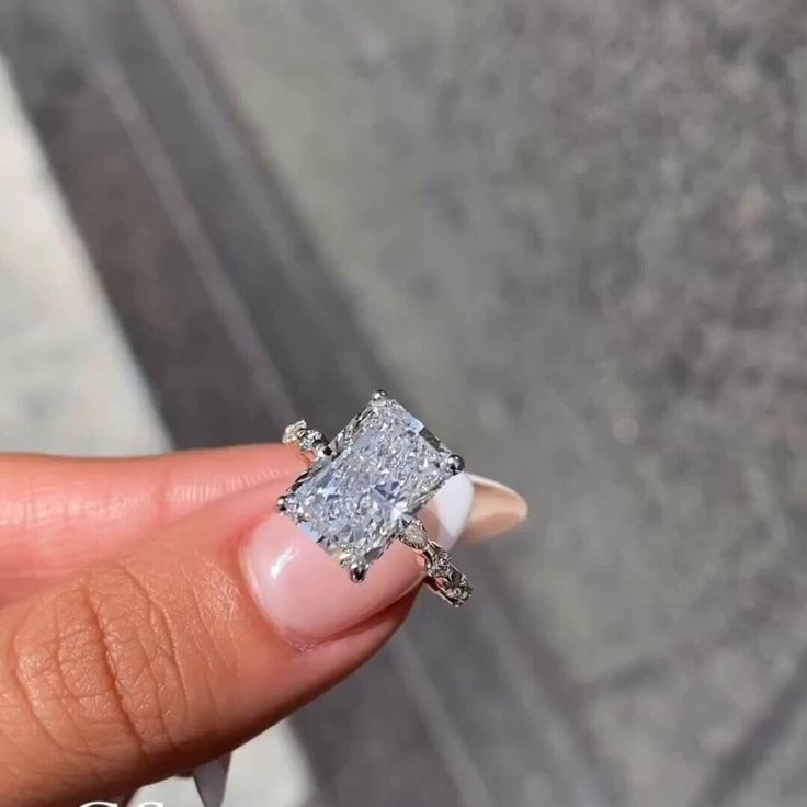 a close up of a person's hand holding an engagement ring