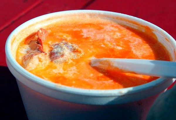 a bowl of soup with a spoon in it on a red tableclothed surface