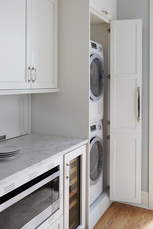 a washer and dryer in a small room with white cabinets on the wall