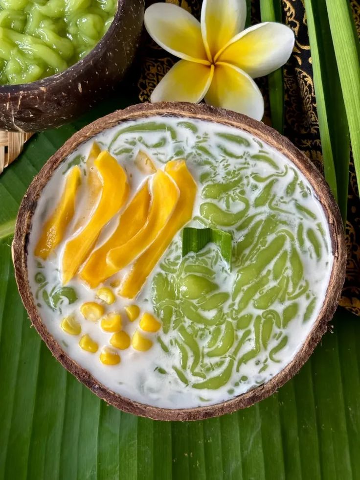 a bowl filled with fruit sitting on top of a green leaf