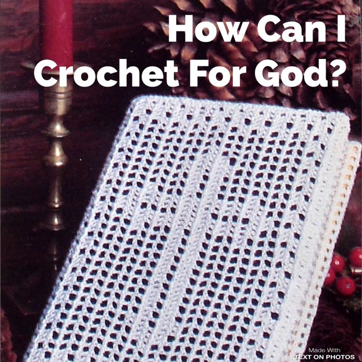 a white crochet blanket sitting next to a candle and pine cone on top of a table