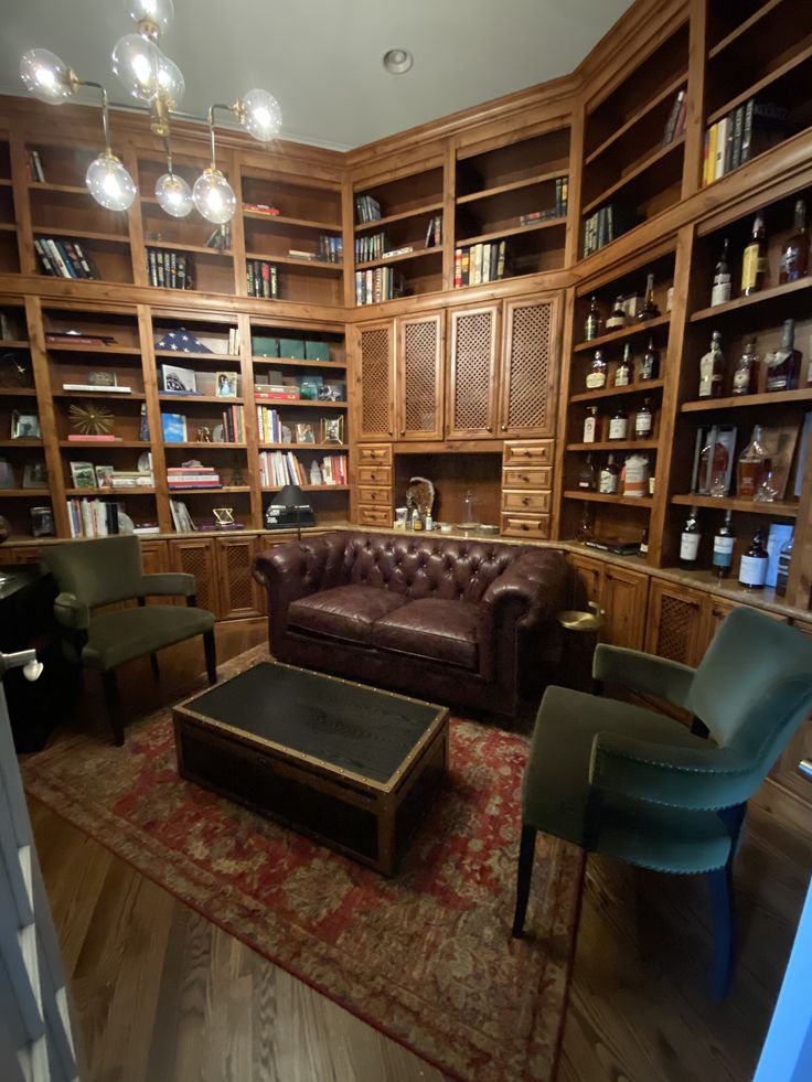 a living room filled with lots of bookshelves and leather couches next to a coffee table