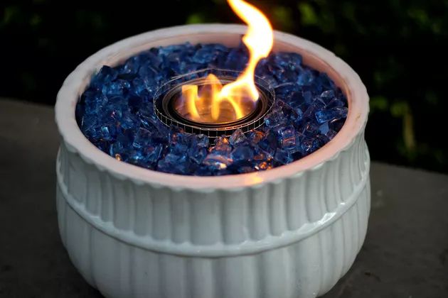 a white bowl filled with blue and yellow fire pit sitting on top of a table