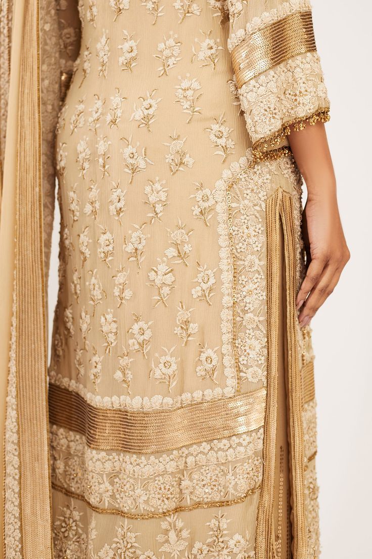 Beige long straight kurta with all-over floral motif thread work and bead tassels. Comes with gold-tone sequin embellished flared pants and dupatta.
Components:3
Embroidered
Neckline:Round
Sleeve Length:Three Quarter
Fabric:Chiffon
Color:Beige
Back keyhole
Bead tassels
Side slits
 - Aza Fashions Bead Tassels, Kurta Set For Women, Straight Kurta, Embroidered Neckline, Flared Pants, Thread Work, Kurta Set, Floral Chiffon, Beaded Tassels