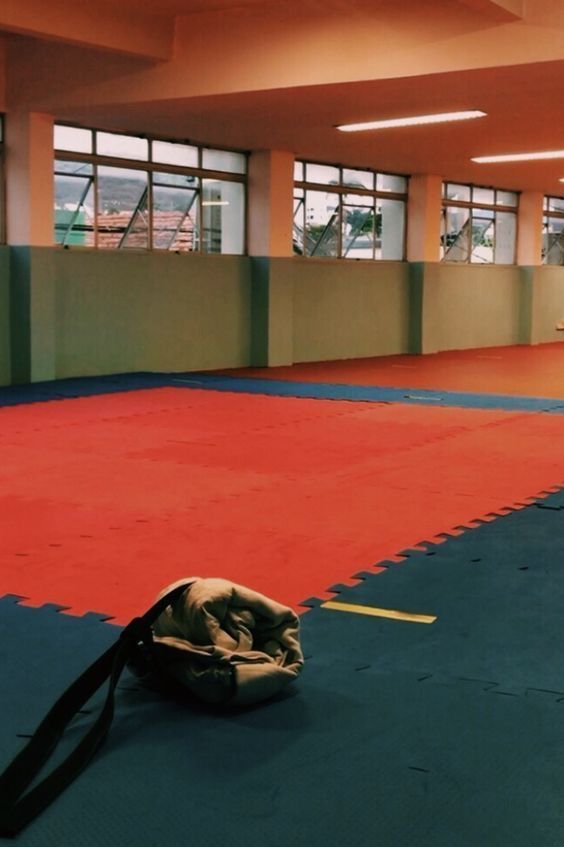 an empty gym room with red and blue mats on the floor is pictured in this image