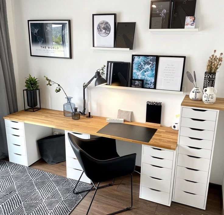 a home office with white cabinets and black chairs in front of a wall full of framed pictures