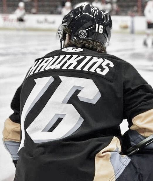 a hockey player sitting on the ice with his back to the camera and holding a stick