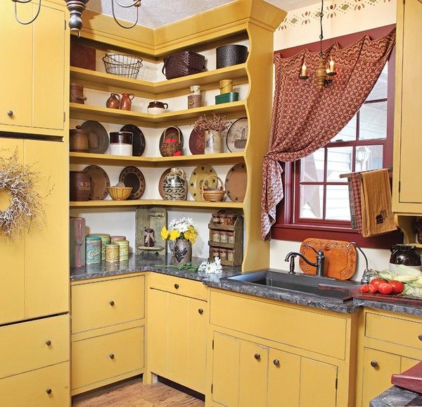 a kitchen with yellow cabinets and black counter tops is pictured in this image, there are dishes on the shelves