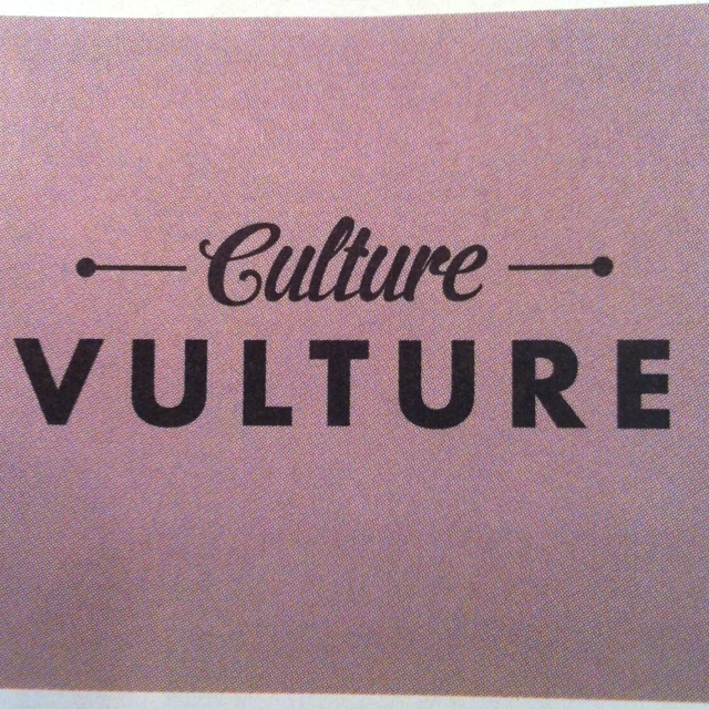 a sign that says culture vulture in black lettering on a pink background with an arrow