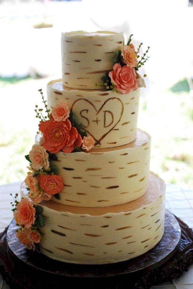 a three tiered wedding cake with flowers on the top and initials on the side