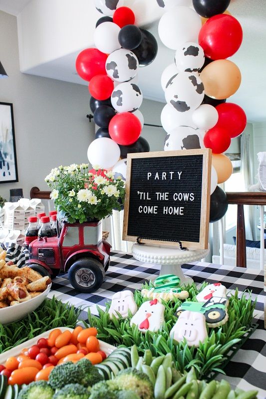 a party table with balloons, food and decorations in the shape of farm animals on it