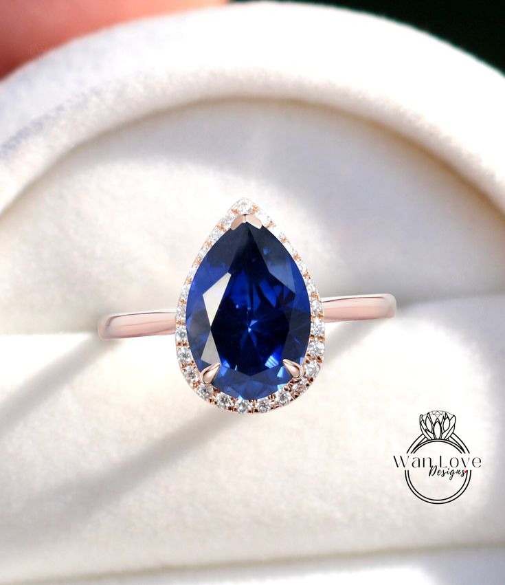 a close up of a ring with a blue stone in the center and diamond accents around it