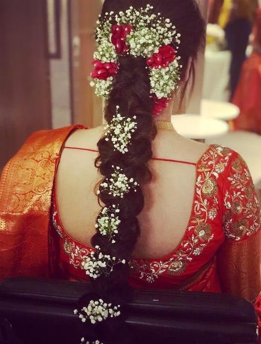 the back of a woman's head with flowers in her hair and an intricate braid