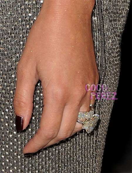 a close up of a person's hand with a diamond ring on her finger