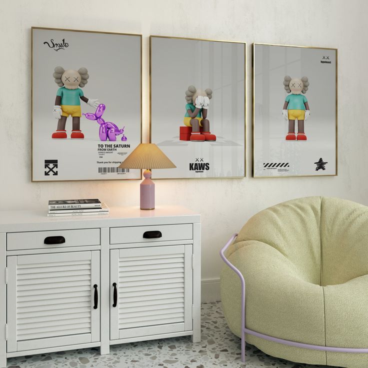 two framed pictures hang on the wall above a white sideboard with drawers and a lamp