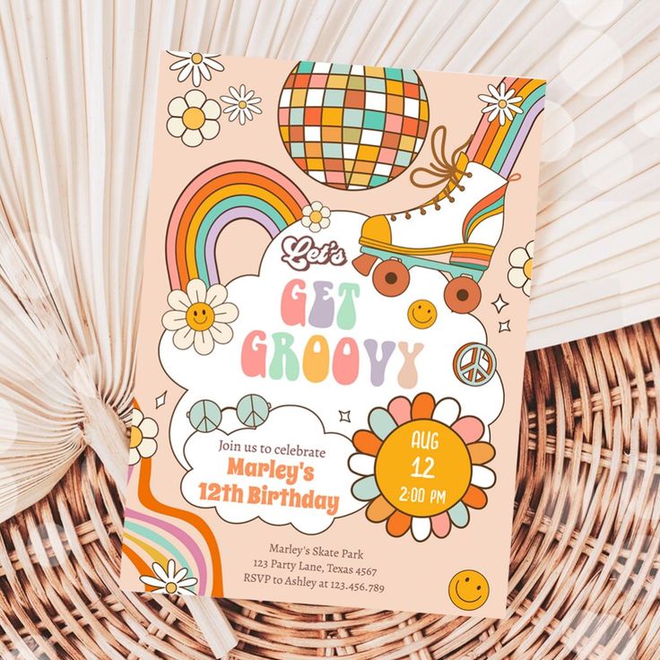 a birthday card with an image of a rainbow and flowers on it, sitting next to some cupcakes