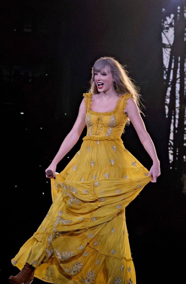 a woman in a yellow dress is performing on stage