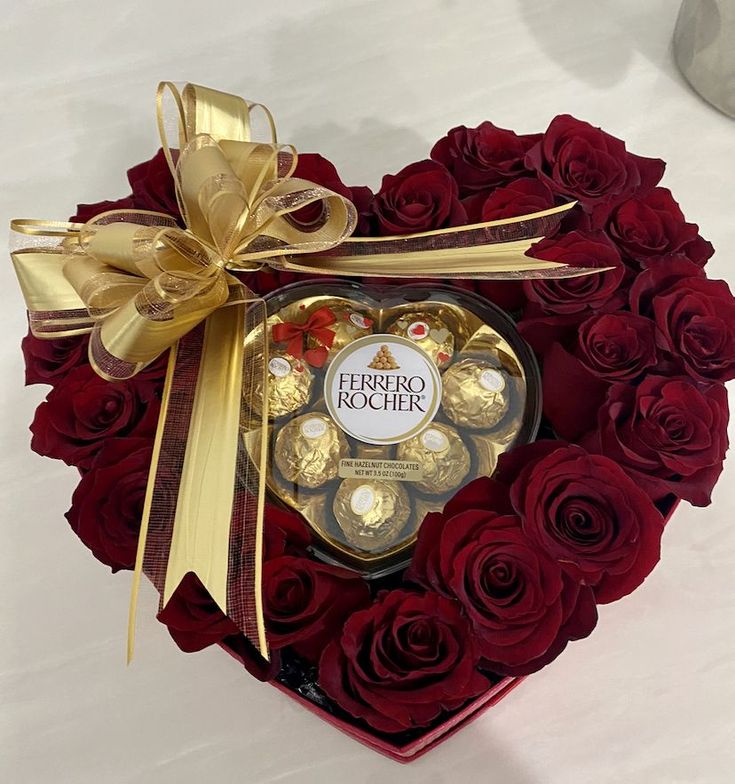 a heart shaped box filled with chocolates and roses