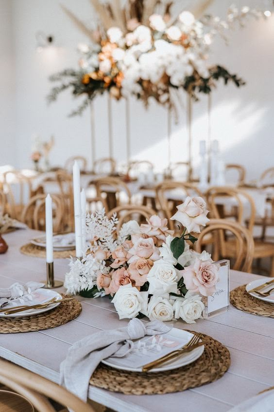 the table is set with white and pink flowers, gold place settings, and candles