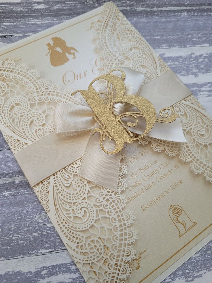 the wedding card is decorated with gold lace and a ribbon, which has a bee on it