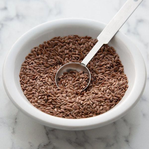 a white bowl filled with brown rice and a spoon in it on a marble surface