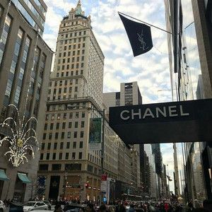 people are walking down the street in front of some tall buildings with chandeliers hanging from them