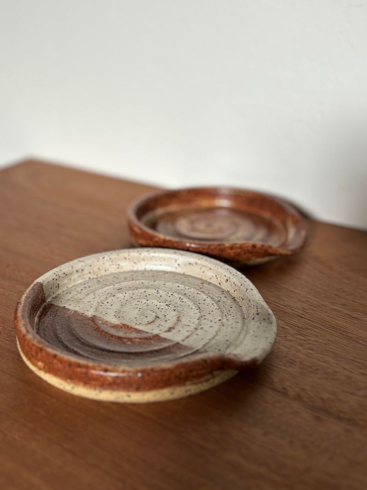 two brown and white bowls sitting on top of a wooden table