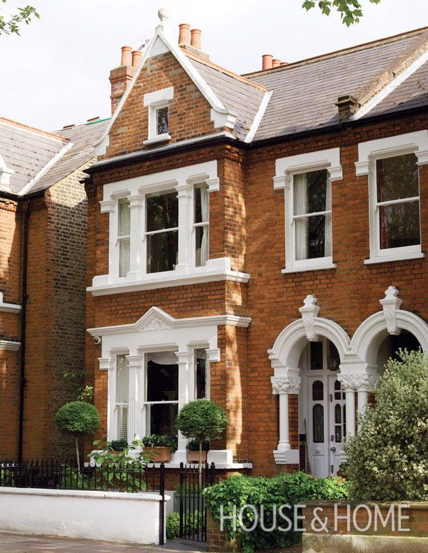 a row of brick houses with white trim and windows on the front, along side a fence