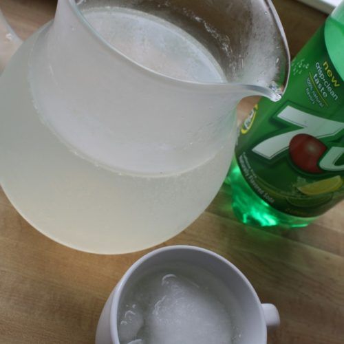 a pitcher of water next to a cup with ice