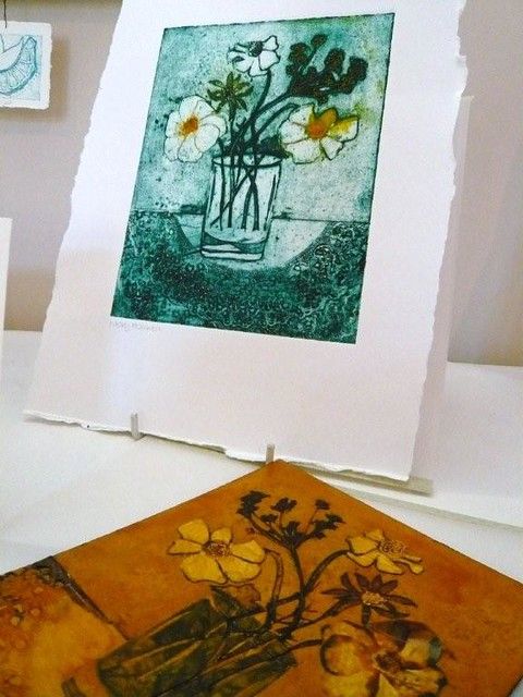 an art piece with flowers in a vase on it next to some other artwork pieces