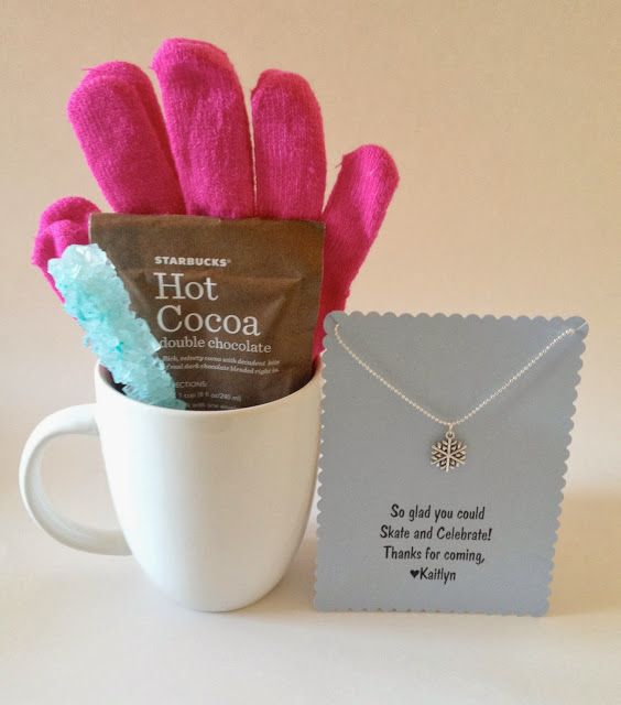 a hot cocoa bag in a mug next to a card and some pink mittens