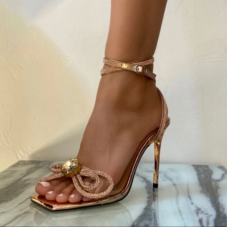 Named After The Queen Of Diamonds, Elizabeth Taylor. Featuring A Sparkling Double Bow And Over Sized Gem Centerpiece. Mirrored Rose Gold Insole And Heel. Double Ankle Strap And Stiletto Heel. Composition: 4.5” Covered Heel Upper: Rose Gold Metallic Pu Sole: Rubber 100% Vegan, Animal And Cruelty-Free Features A Buckle Fastening Ankle Strap Imported Rose Gold Open Toe Heels With 4-inch Heel, Feminine Open Toe Heels For Party, Elegant Pink Sandals For Night Out, Feminine 4-inch Heel Sandals For Parties, Feminine Sandals With 4-inch Heel For Party, Feminine Fitted Sandals For Party, Glamorous Ankle Strap Heels For Cocktail, Feminine Open Heel Evening Heels, Feminine Cocktail Heels With Sculpted Heel