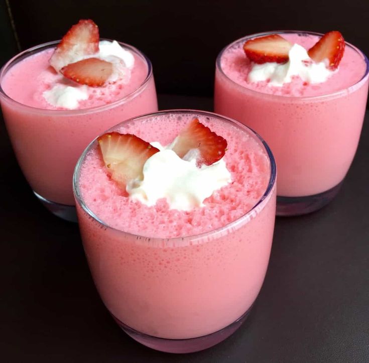 three glasses filled with pink liquid and topped with strawberries