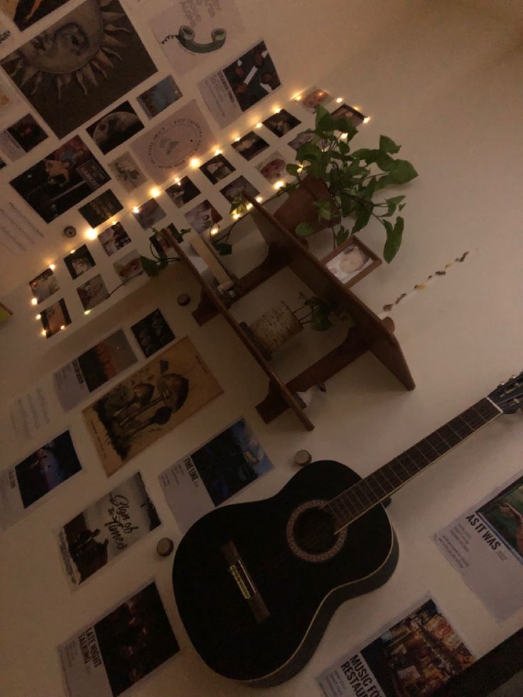 a guitar is sitting on the floor in front of a wall with pictures and lights