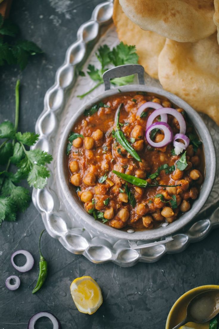 a bowl filled with chickpeas and onions next to some pita breads