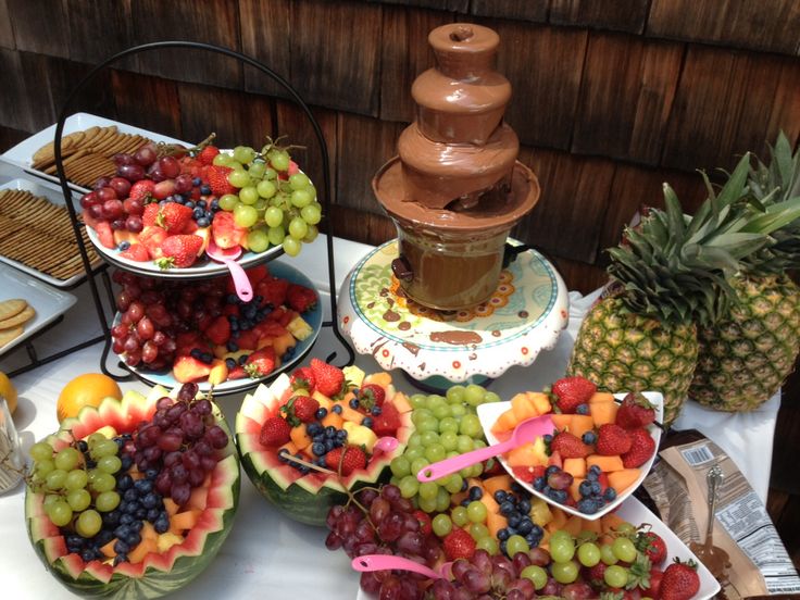 a table topped with lots of different types of fruit on plates next to a water fountain