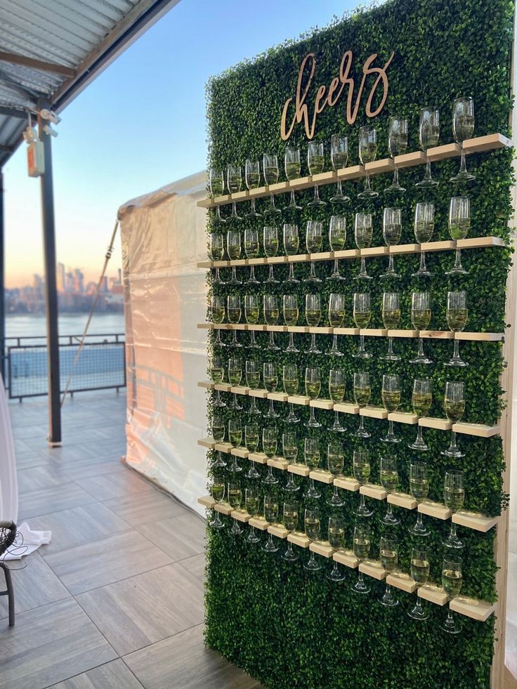 a wall covered in green plants and glasses