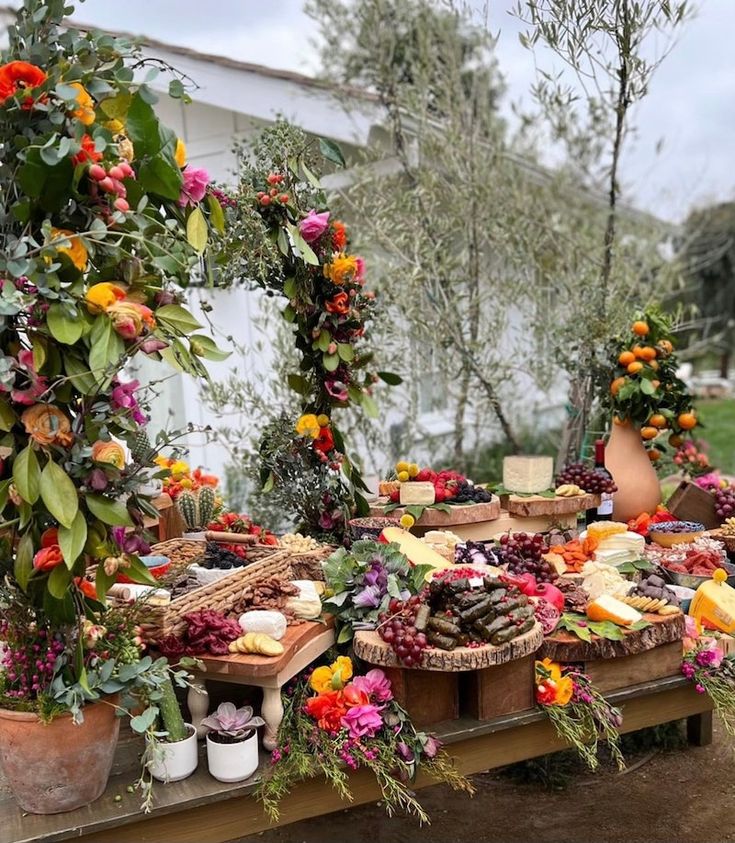 an assortment of food is displayed on a wooden table with potted plants and flowers