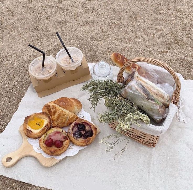 an assortment of breads and pastries on a towel with drinks in the background