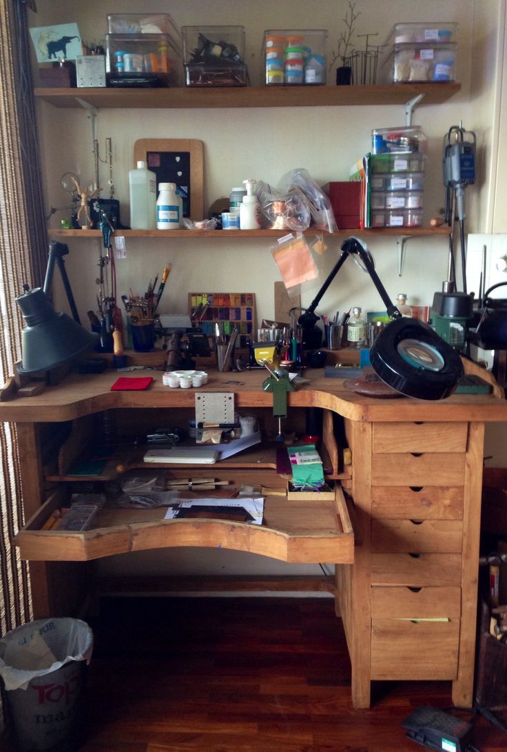 a wooden desk with lots of clutter on top of it in front of a window