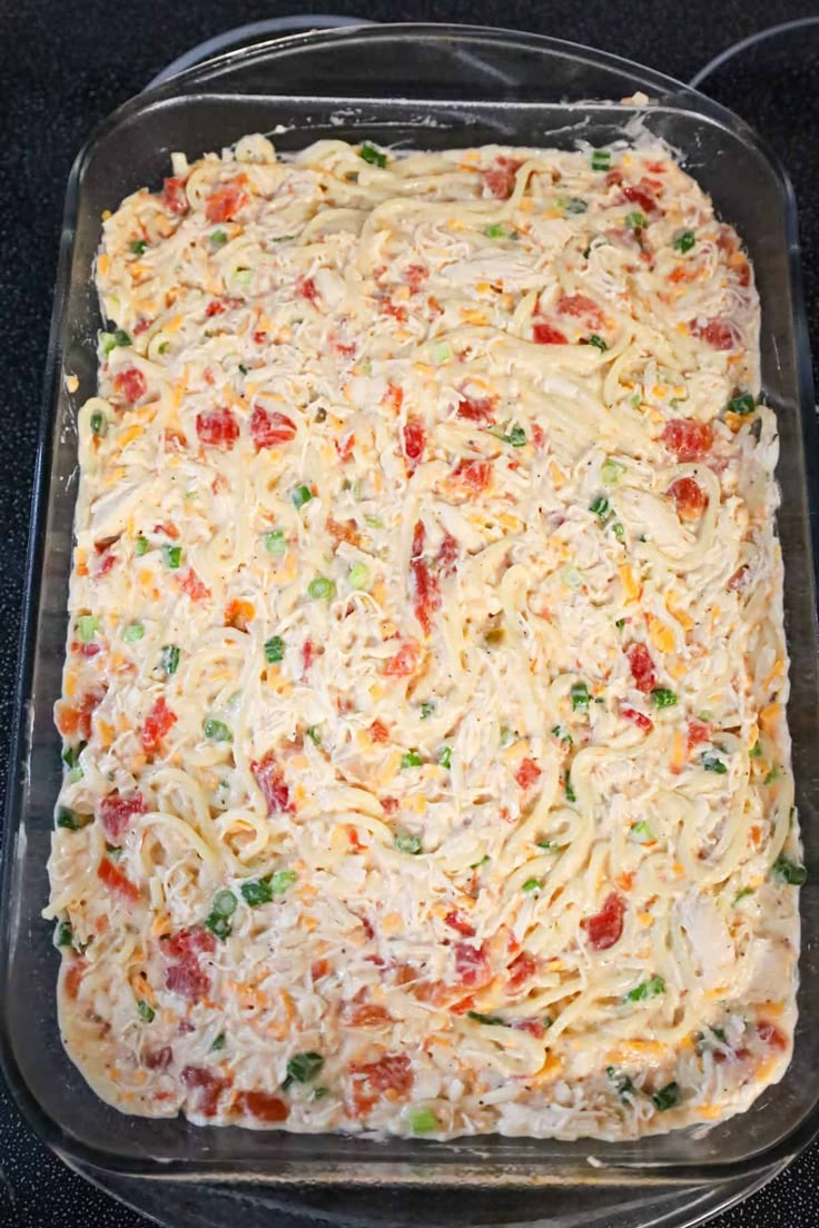 an uncooked casserole in a glass dish on a black counter top