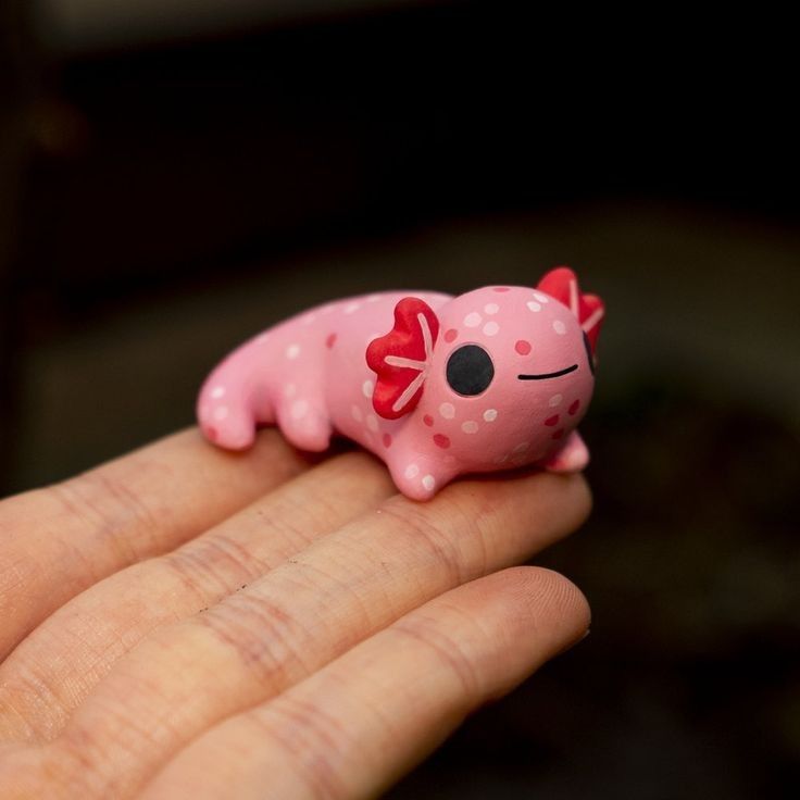 a small pink toy pig sitting on top of someone's hand