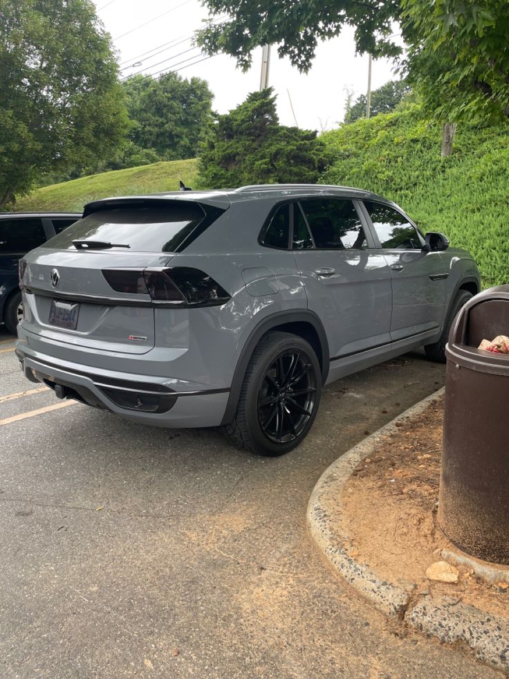 a grey car parked next to a trash can