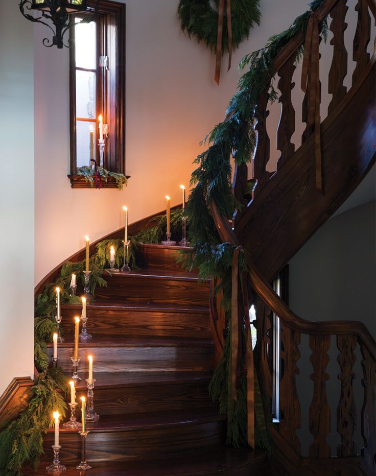 candles are lit on the stairs in front of an open window and wreathed garland