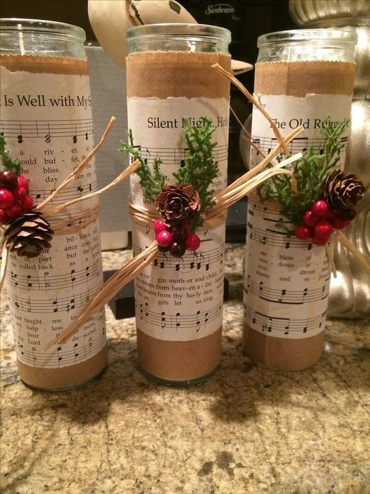 three jars with christmas decorations on them sitting on a counter top next to some candles