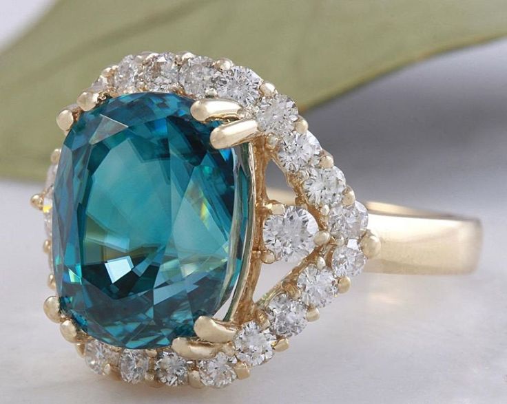 8.70 Carats Natural Very Nice Looking Blue Zircon and Diamond 14K Yellow Gold Ring Suggested Replacement Value: 9,000.00 Total Natural Cushion Shaped Zircon Weights: Approx. 7.80 Carats Zircon Measures: 11 x 8.4mm Natural Round Diamonds Weight: .90 Carats (color G-H / Clarity SI1-SI2) Ring total weight: 5.2 grams Disclaimer: all weights, measurements and colors are approximate and may vary slightly from the listed dimensions or as seen in the image. All pictures are magnified to show the smalles Luxury Blue Topaz Ring Gia Certified, Blue Gia Certified Emerald Ring For Formal Occasions, Luxury Blue Moissanite Rings, Formal Blue Topaz Ring With Moissanite, Luxury Blue Moissanite Jewelry, Formal Turquoise Jewelry With Halo Setting, Blue Emerald Halo Setting Ring, Elegant Blue Emerald Ring With Brilliant Cut, Blue Emerald Rings With Halo Setting